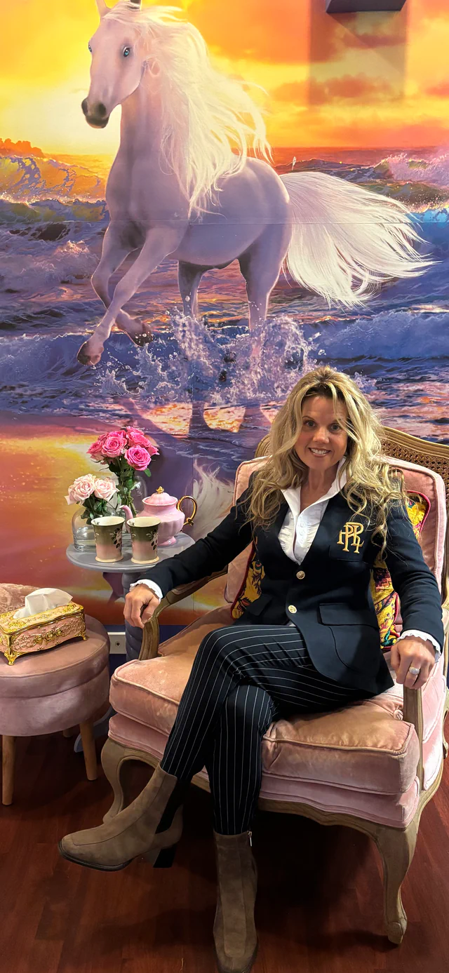 Jasmyn seated in her HeartSoul clinic at Hope Island, beside flowers and horse artwork